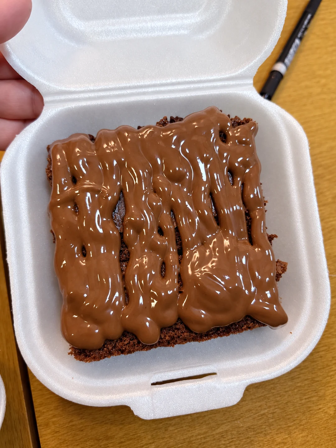 Fatia de bolo de chocolate com cobertura em embalagem